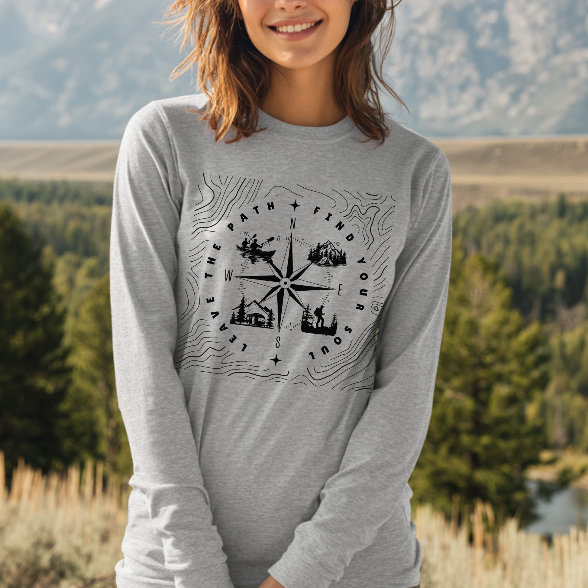 Person wearing a gray long-sleeve shirt with a compass design in a natural setting