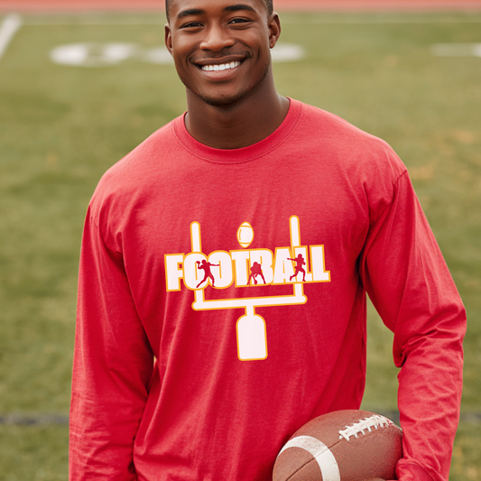 Man wearing a red long-sleeve shirt with a football design, holding a football on a sports field.
