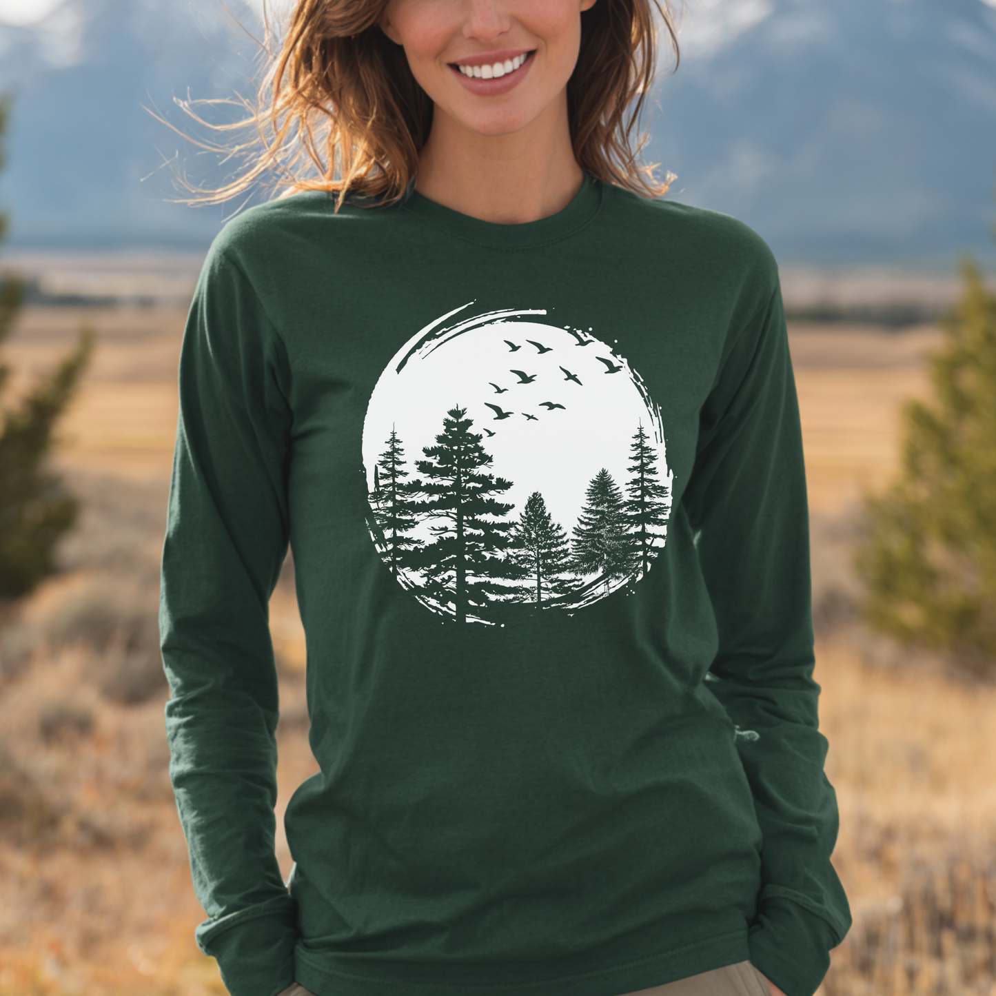 Person wearing a green long-sleeve shirt with a nature graphic in a scenic outdoor setting