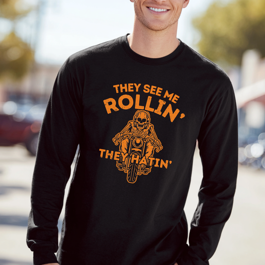 Person wearing a black long-sleeve shirt with orange text and graphic, standing outdoors.