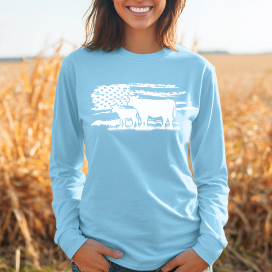 Person wearing a light blue long-sleeve shirt with a white graphic design in a field.