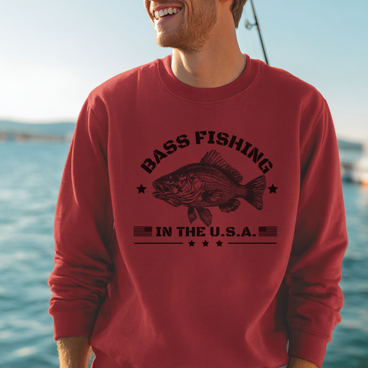 Man wearing a red sweatshirt with a bass fishing design by a body of water.