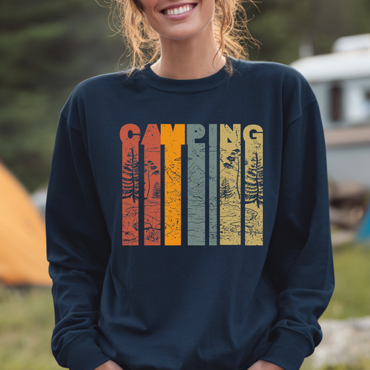 Person wearing a navy blue sweatshirt with 'Camping' graphic design outdoors.