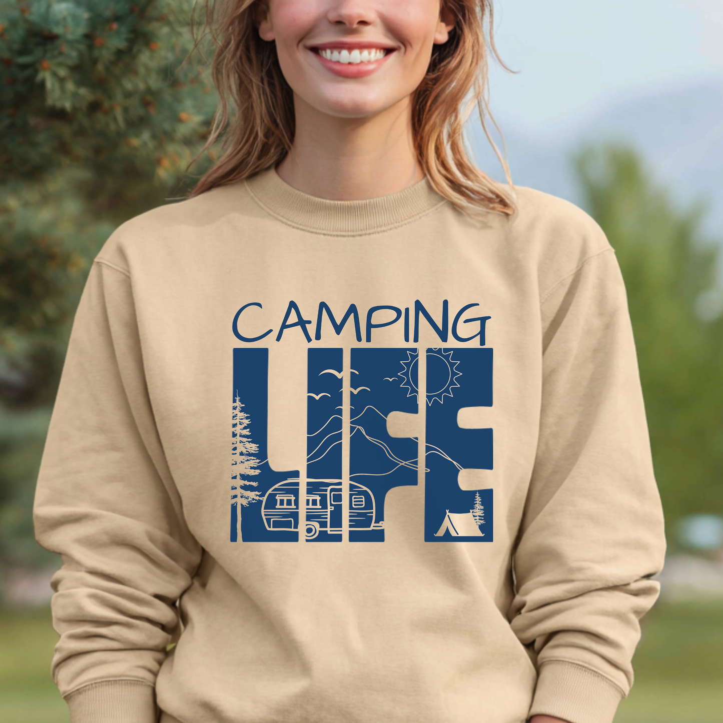 Person wearing a beige sweatshirt with 'Camping Life' graphic design outdoors.