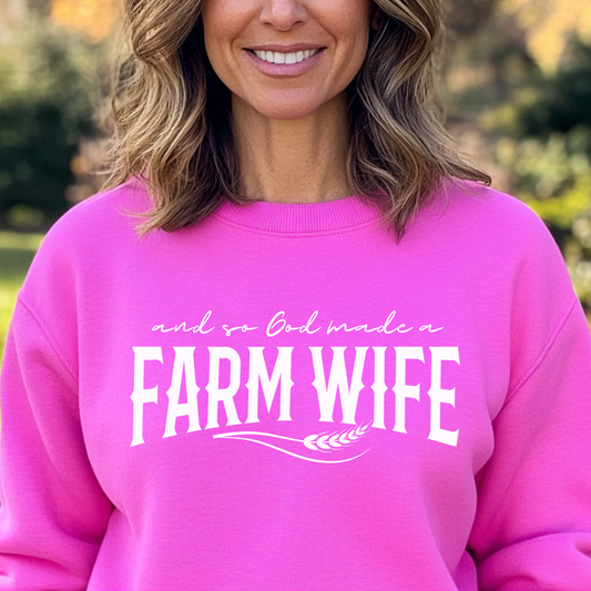 Person wearing a pink sweatshirt with 'Farm Wife' text outdoors