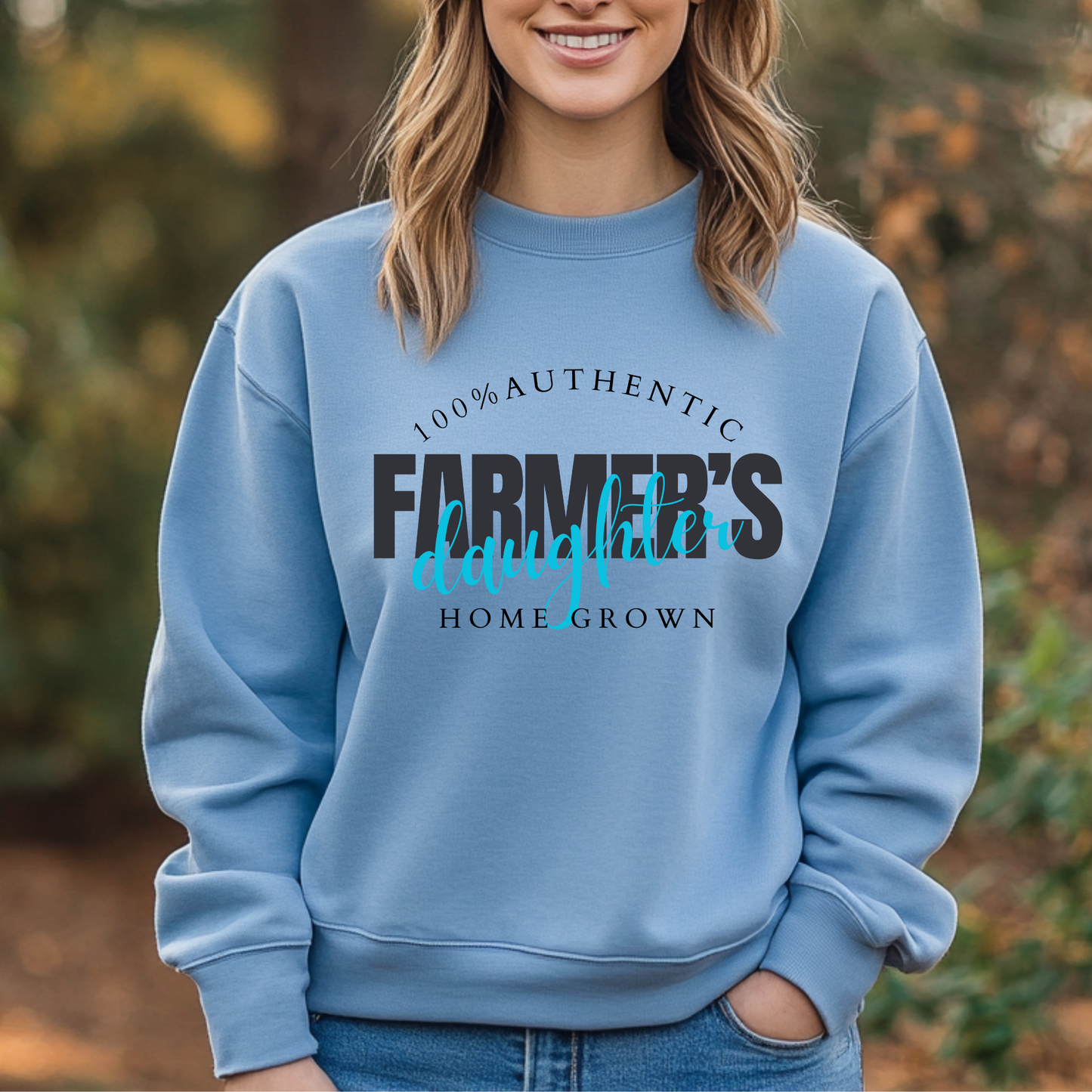Person wearing a blue sweatshirt with '100% Authentic Farmer's Daughter Home Grown' text outdoors.