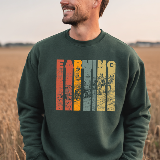 Man wearing a green sweatshirt with 'Farming' graphic in a field