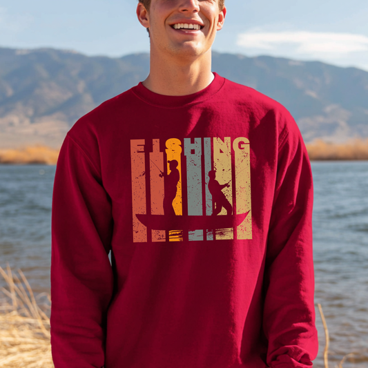 Person wearing a red sweatshirt with 'Fishing' graphic by a body of water with mountains in the background