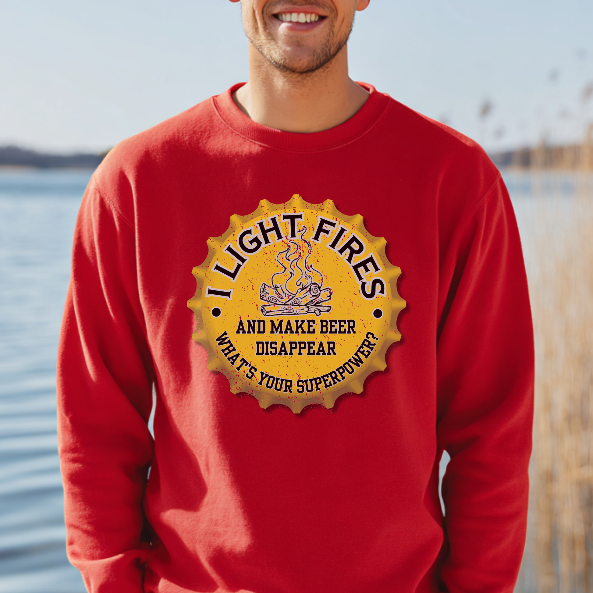 Person wearing a red sweatshirt with a yellow graphic and text by a body of water.