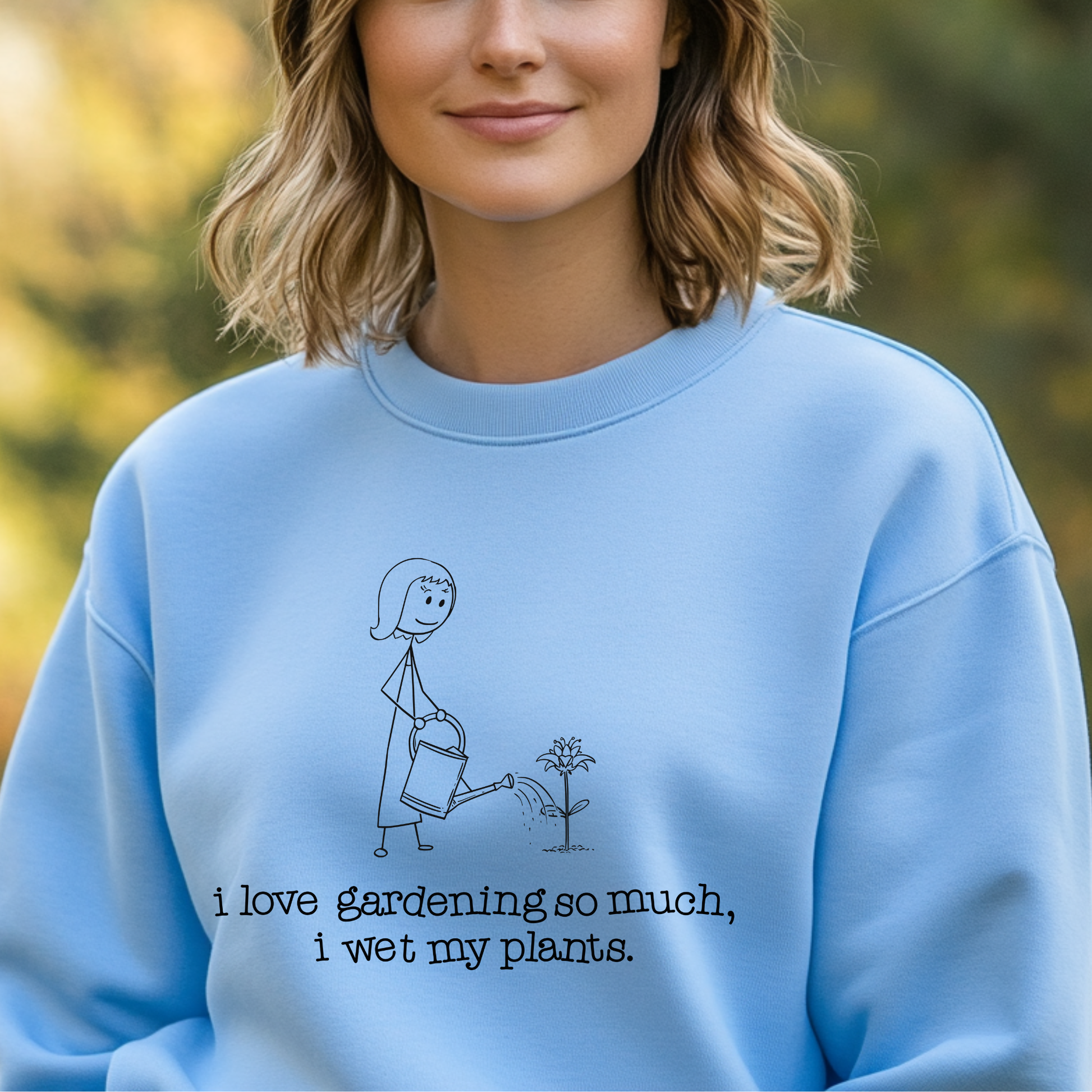 Person wearing a light blue sweatshirt with a gardening graphic and text.