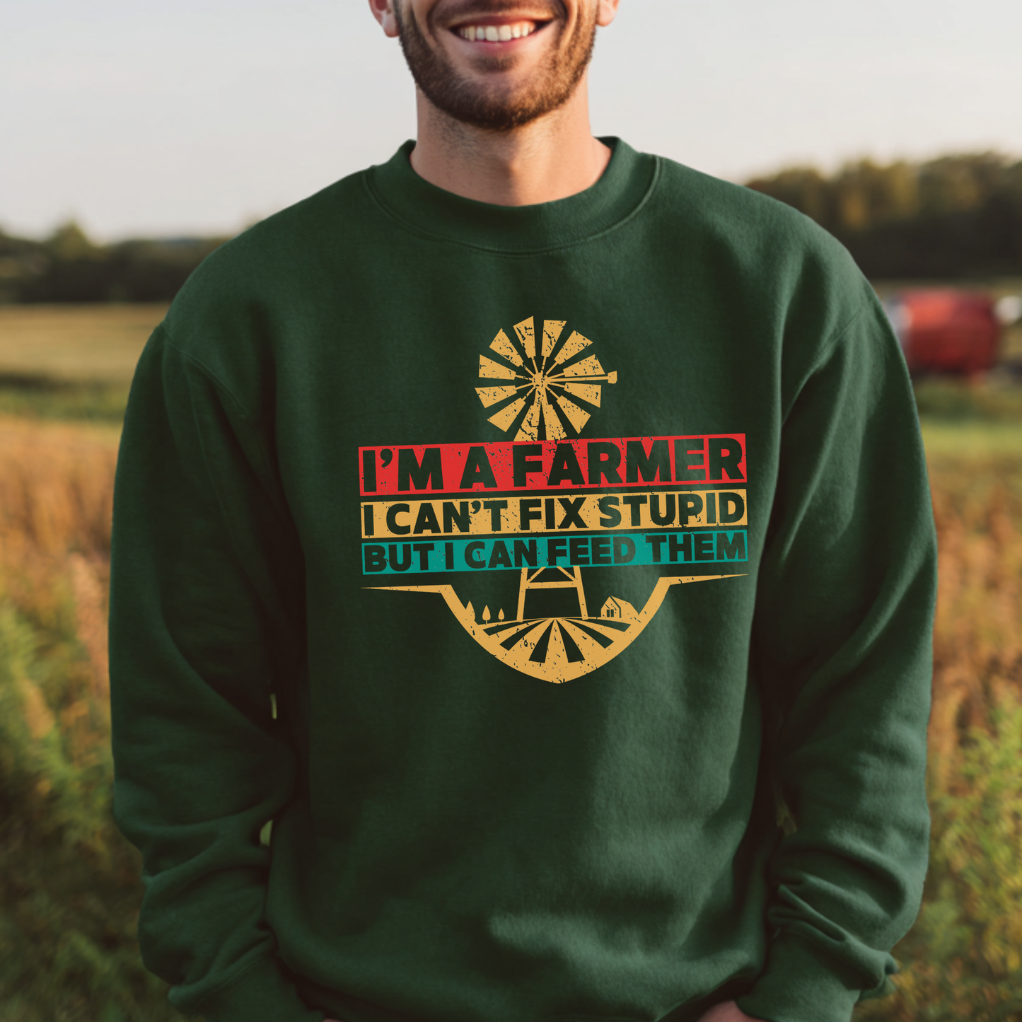 Man wearing a green sweatshirt with a farmer-themed design in a field.