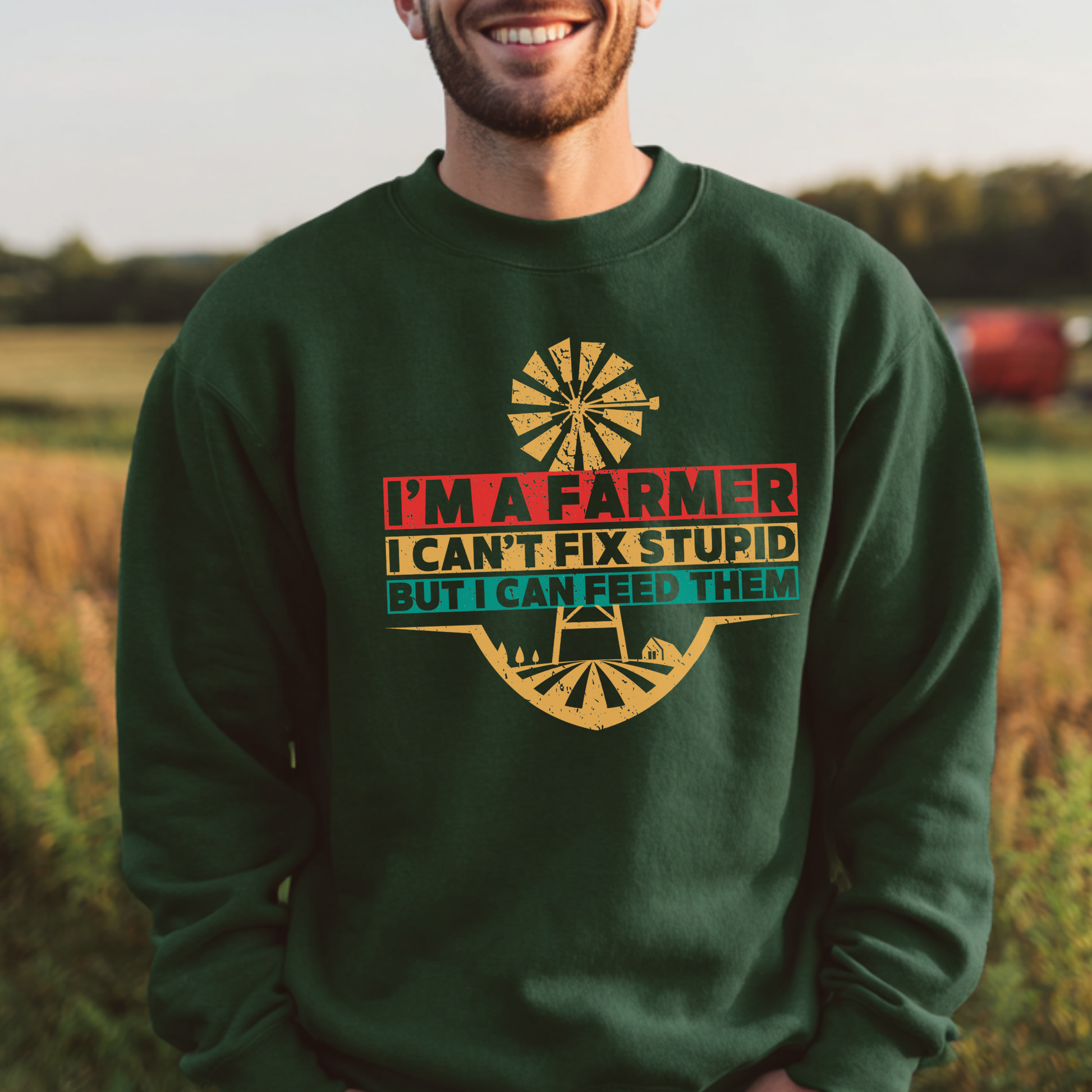 Man wearing a green sweatshirt with a farmer-themed design in a field.