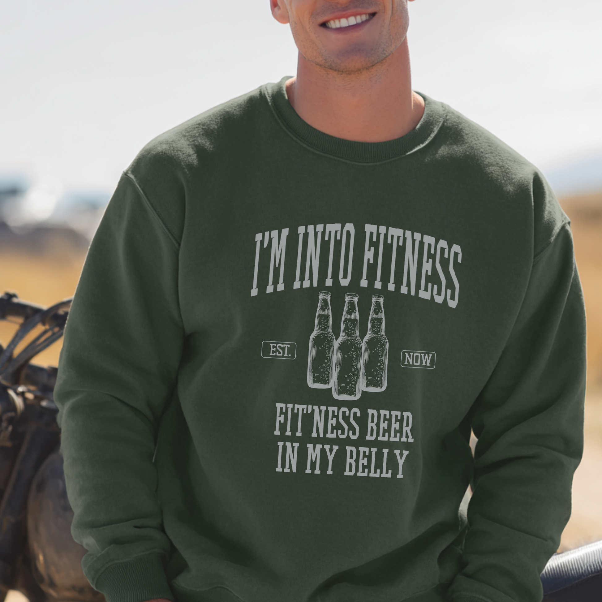 Person wearing a green sweatshirt with humorous fitness and beer text design.