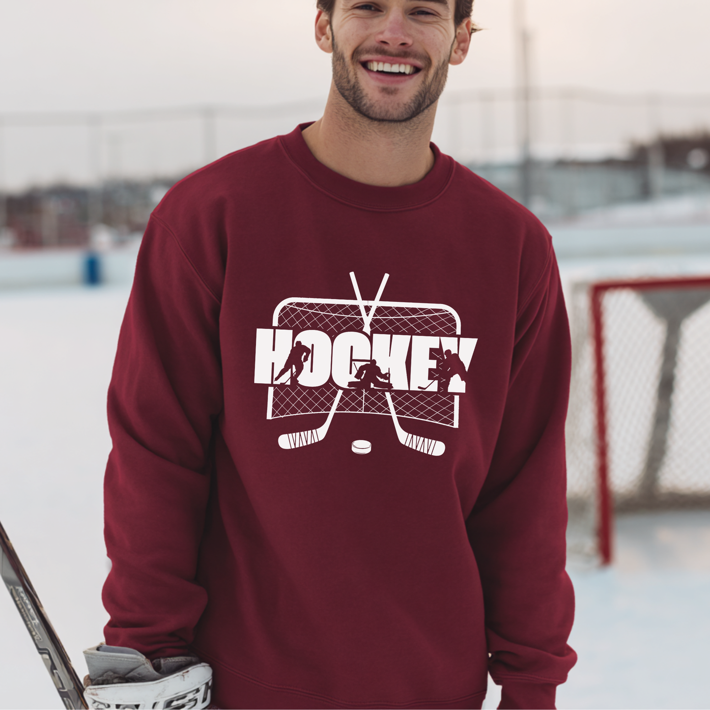 Man wearing a maroon sweatshirt with a hockey graphic on an ice rink.