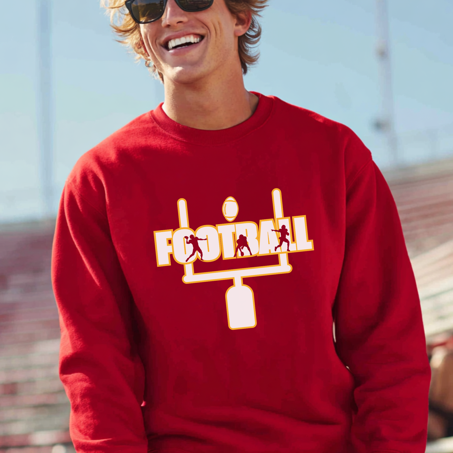 Person wearing a red sweatshirt with a football design outdoors.