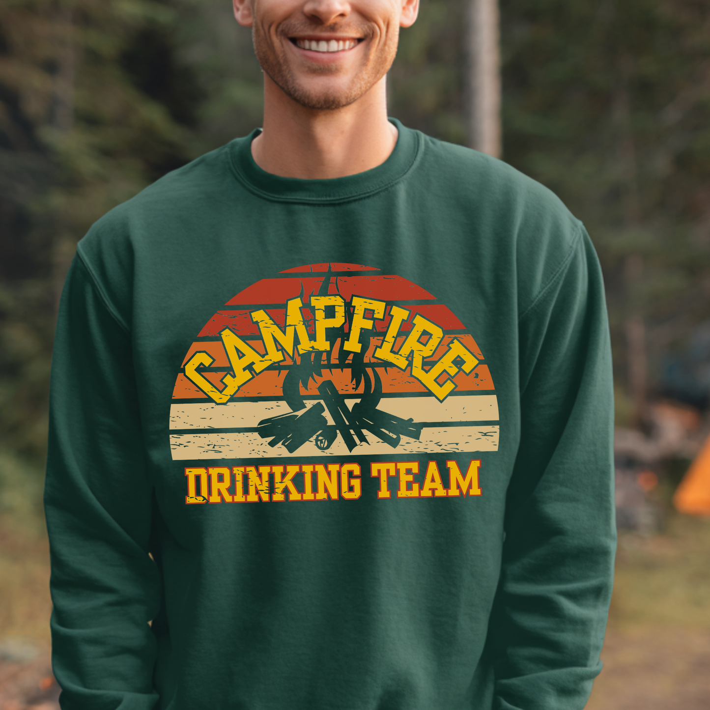 Man wearing a green sweatshirt with 'Campfire Drinking Team' design in a forest setting