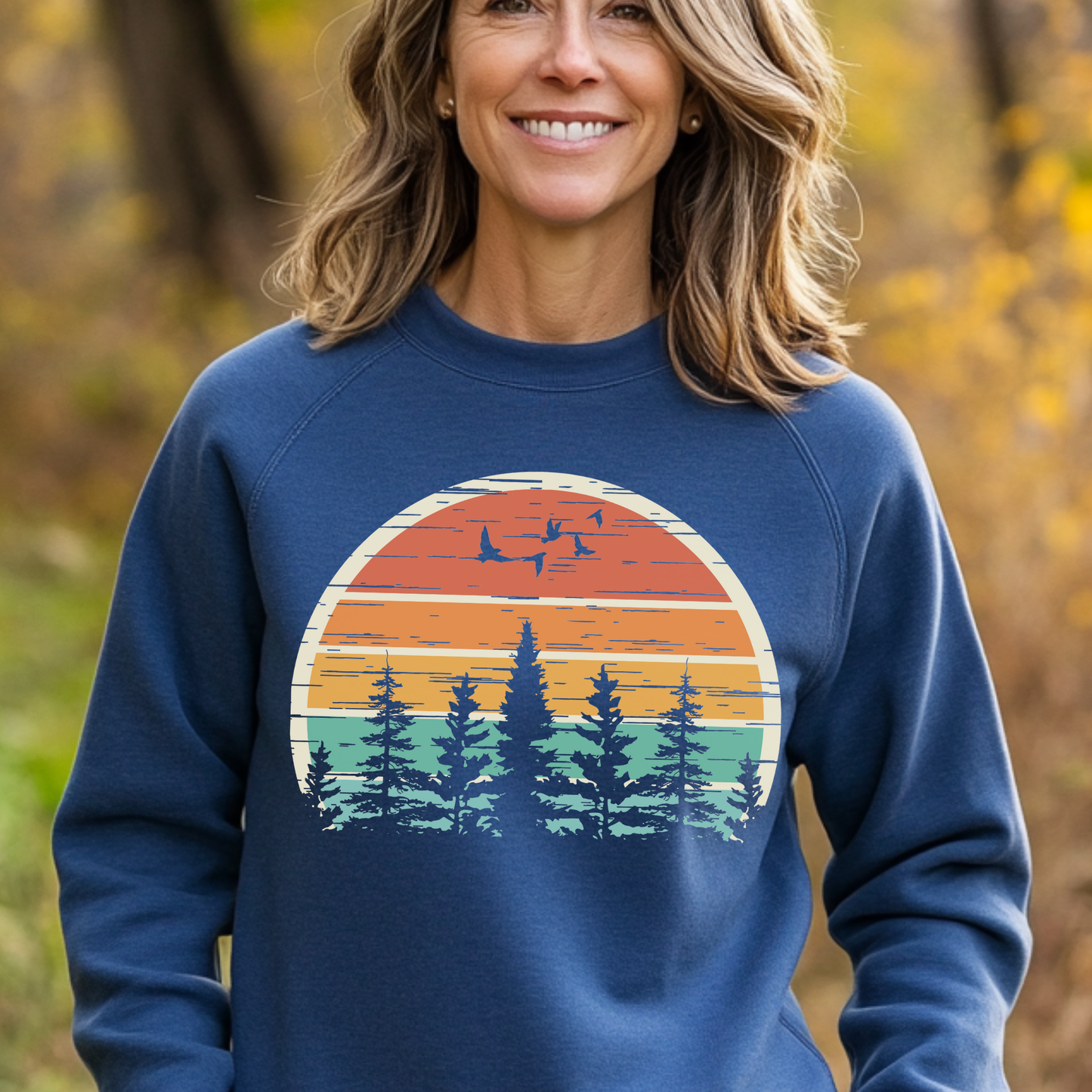 Woman wearing a blue sweatshirt with a nature-themed design outdoors.