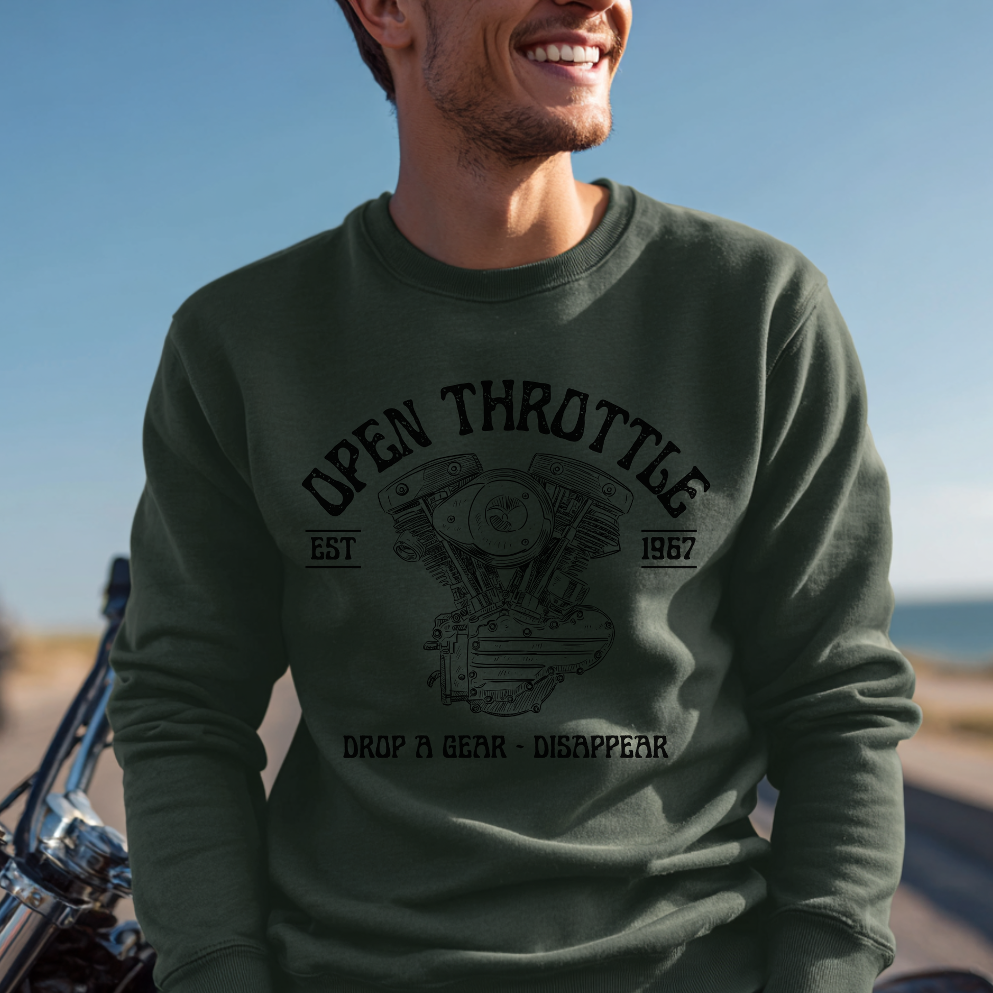 Man wearing a green sweatshirt with 'Open Throttle' text and engine graphic, standing next to a motorcycle.