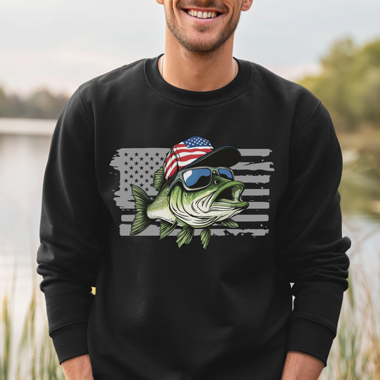 Person wearing a black sweatshirt with a fish graphic and American flag design, standing outdoors by a body of water.