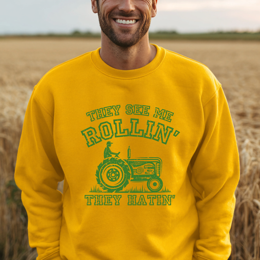Man wearing a yellow sweatshirt with green text and graphic in a field