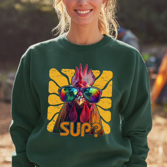 Person wearing a green sweatshirt with a rooster graphic and 'SUP?' text outdoors.