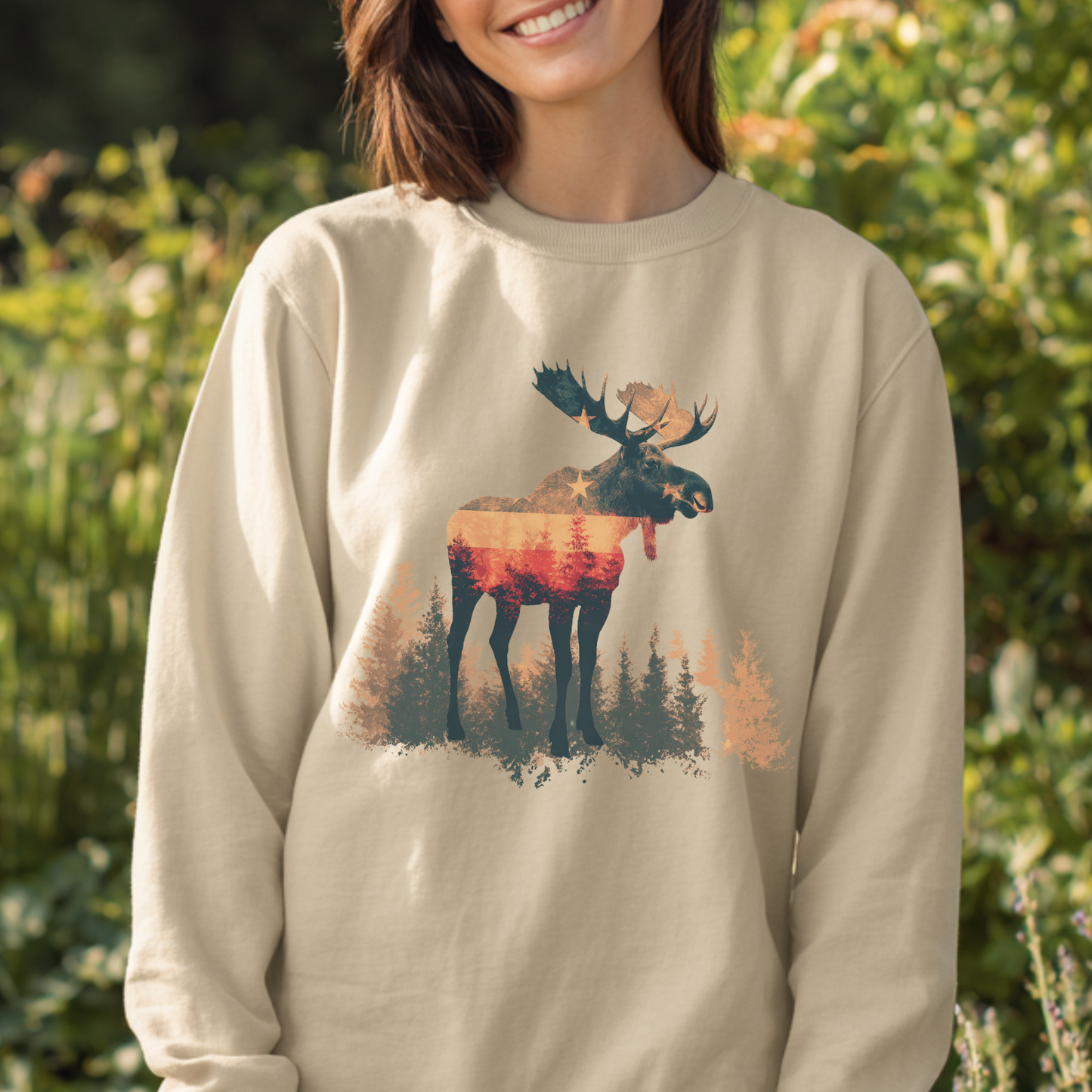 Person wearing a beige sweatshirt with a moose graphic in a natural setting