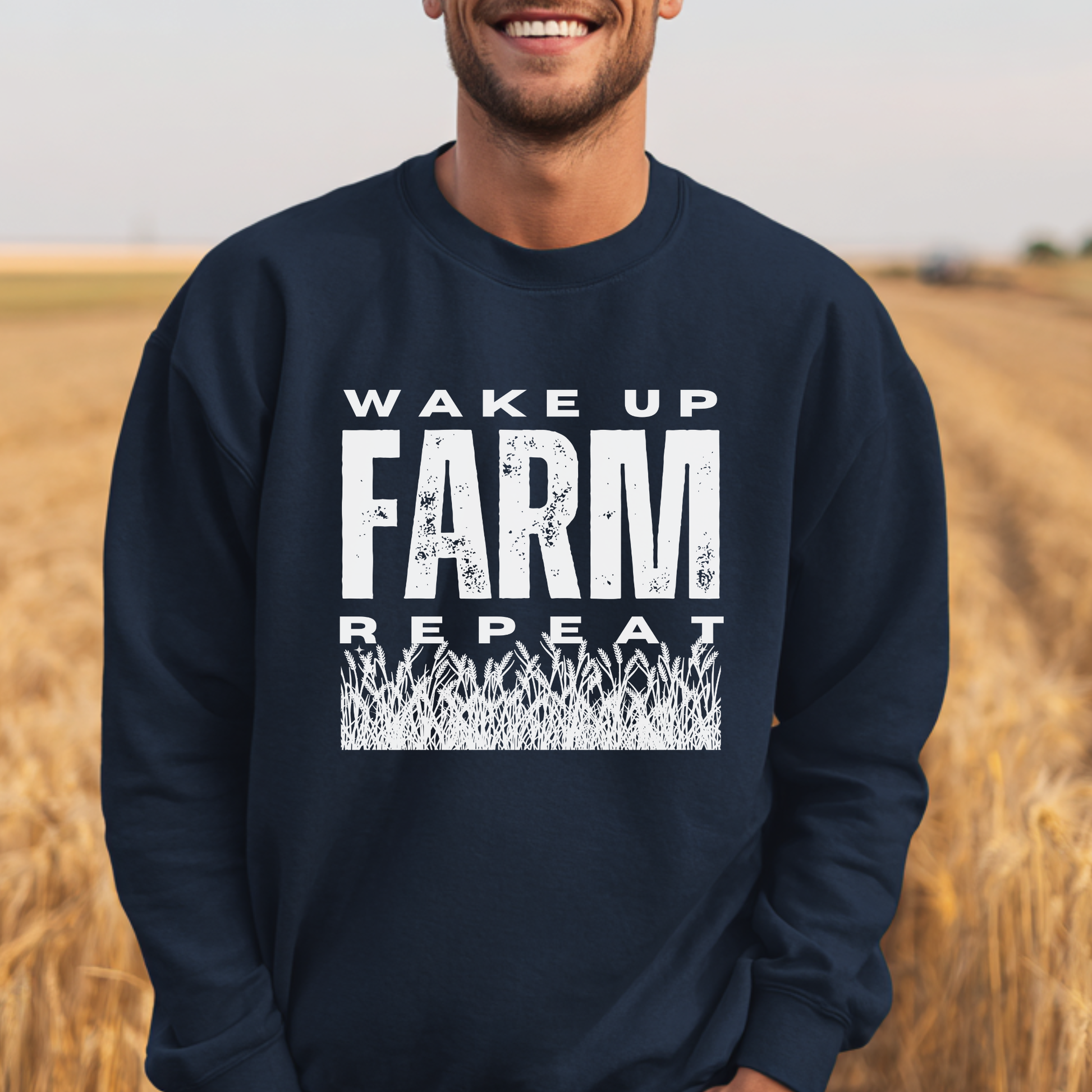 Person wearing a navy blue sweatshirt with 'Wake Up Farm Repeat' text in a field.