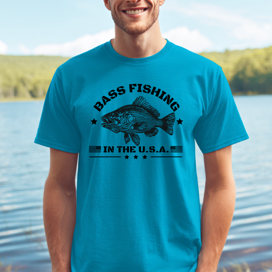 Man wearing a blue t-shirt with a bass fishing graphic by a lake.