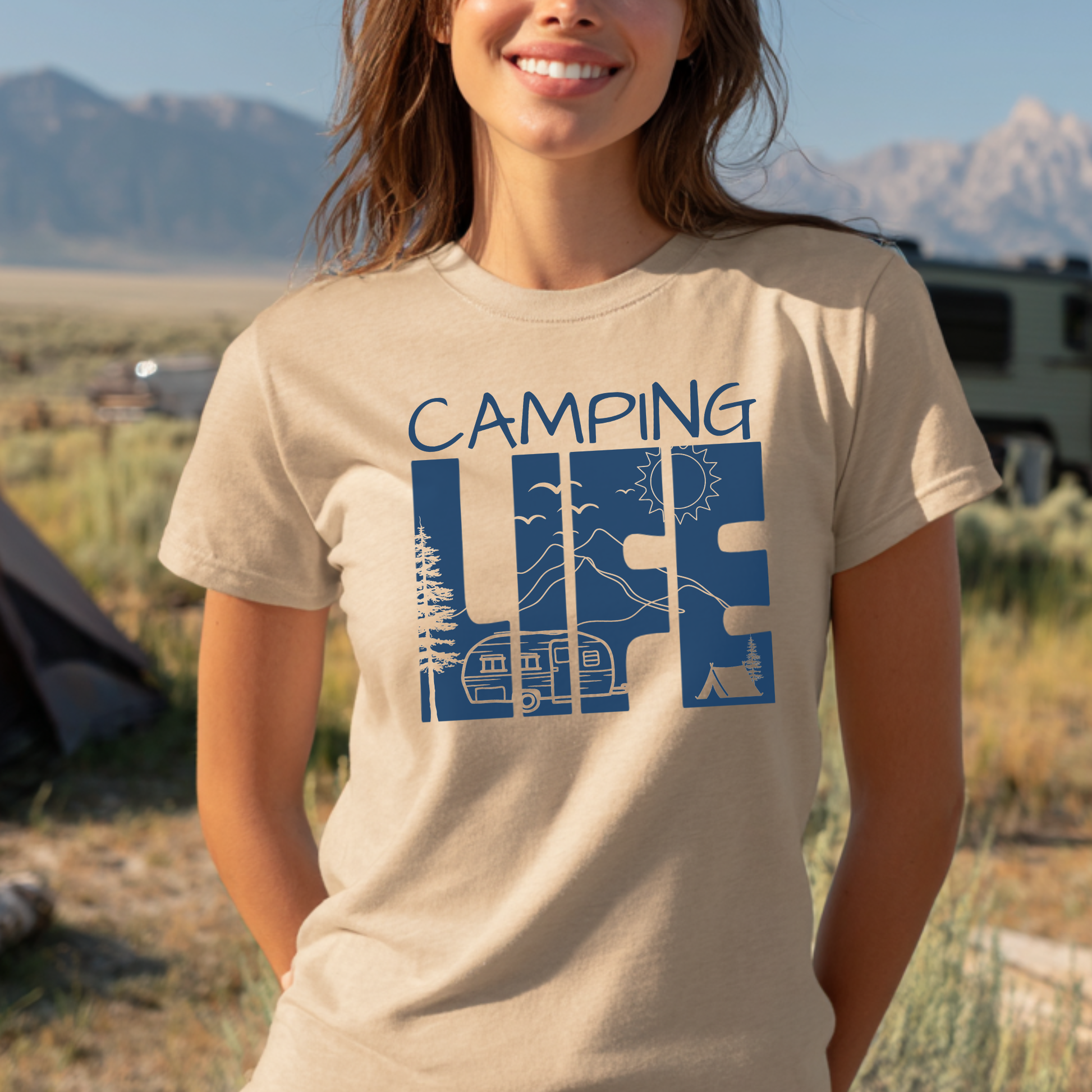 Person wearing a 'Camping Life' t-shirt with a scenic design in a camping setting.