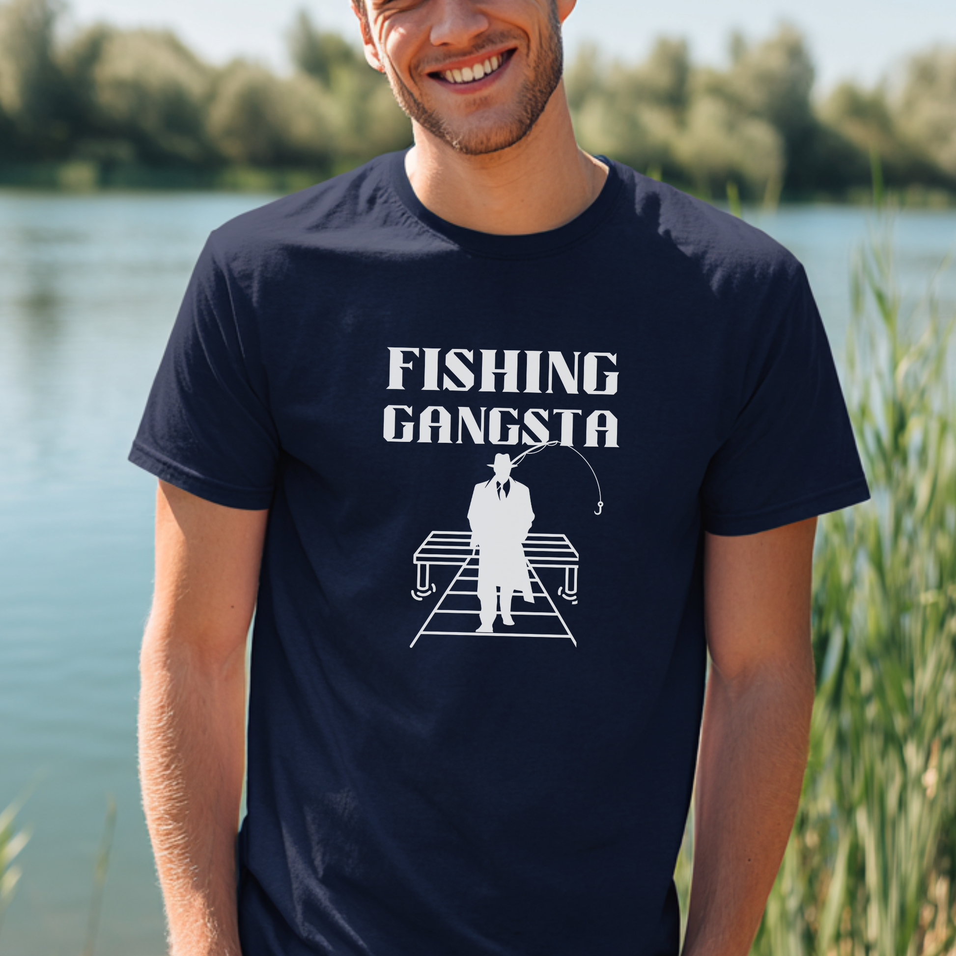 Man wearing a navy blue t-shirt with 'Fishing Gangsta' graphic by a lake.