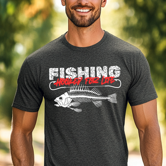 Man wearing a dark gray t-shirt with 'Fishing Hooked for Life' graphic outdoors.