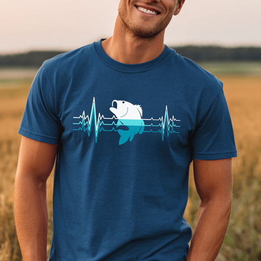 Man wearing a blue t-shirt with a graphic design of a fish and heartbeat lines, standing in a field.