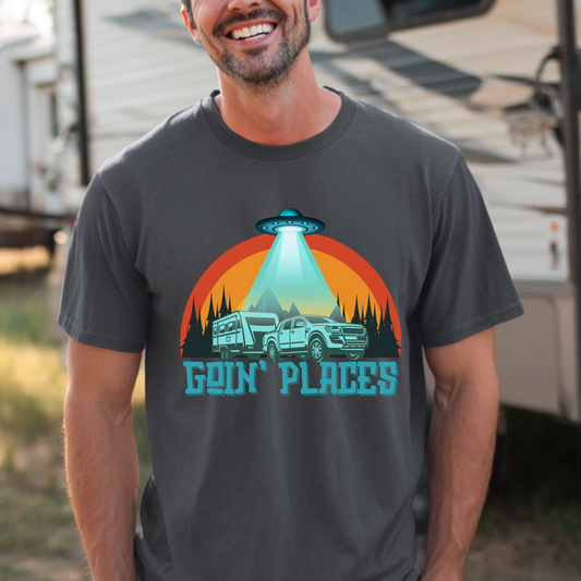 Man wearing a t-shirt with a UFO and truck graphic and 'Goin' Places' text, standing in front of an RV.