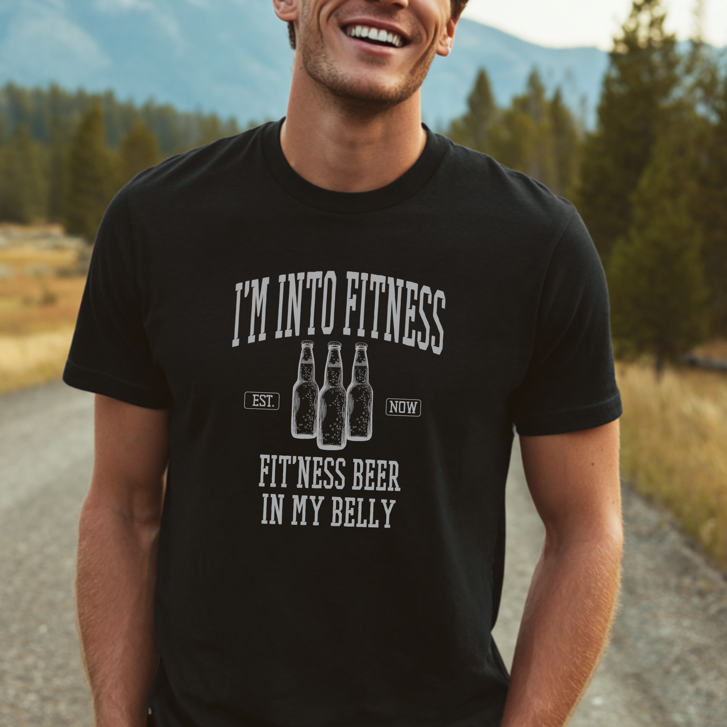 Man wearing a black t-shirt with humorous fitness and beer text, standing outdoors.