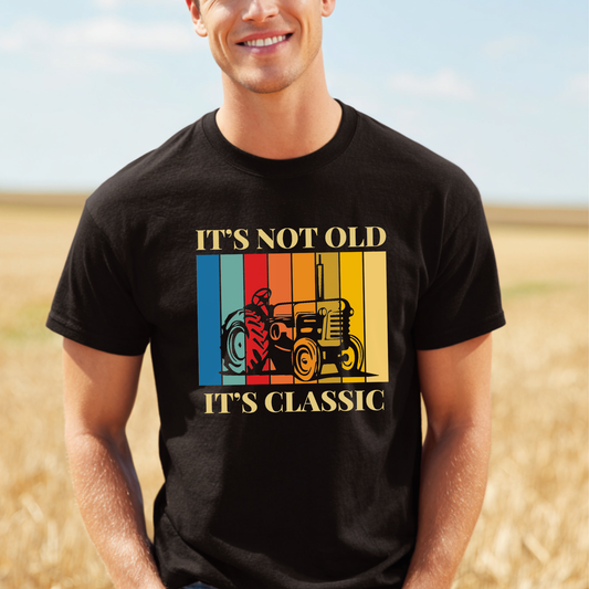 Man wearing a black t-shirt with a colorful graphic and text in a field.