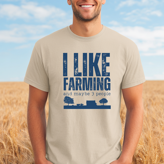 Person wearing a t-shirt with 'I Like Farming and maybe 3 people' text in a field.