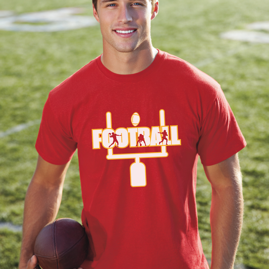 Man wearing a red t-shirt with a football graphic on a grassy field
