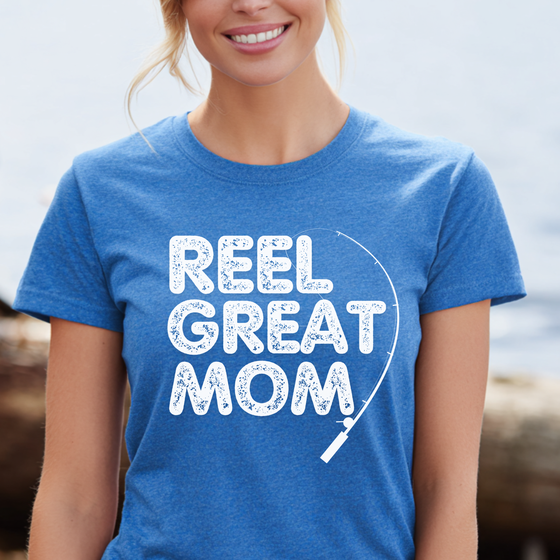 Person wearing a blue t-shirt with 'REEL GREAT MOM' text and fishing reel graphic.
