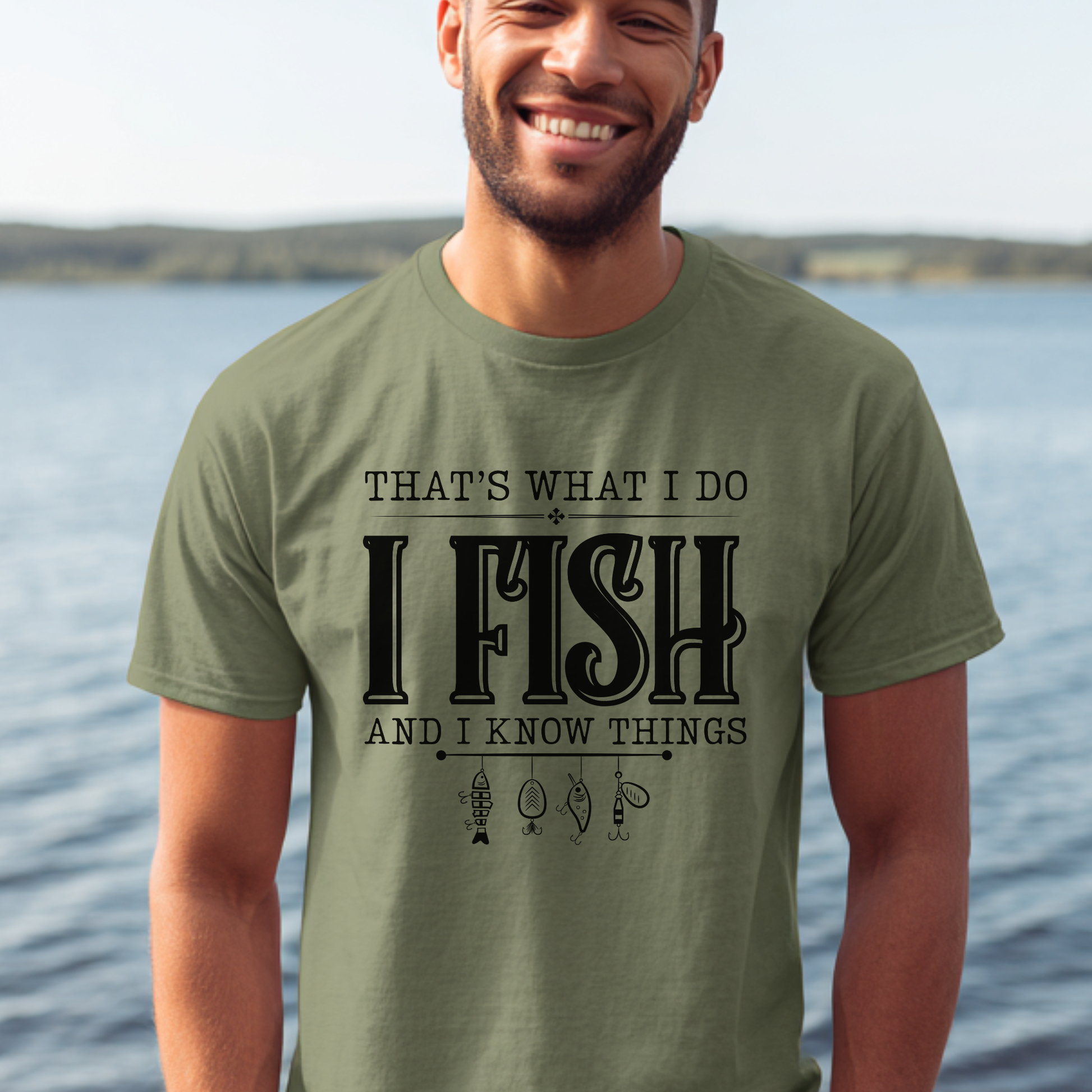 Man wearing a green t-shirt with fishing-themed text by a body of water