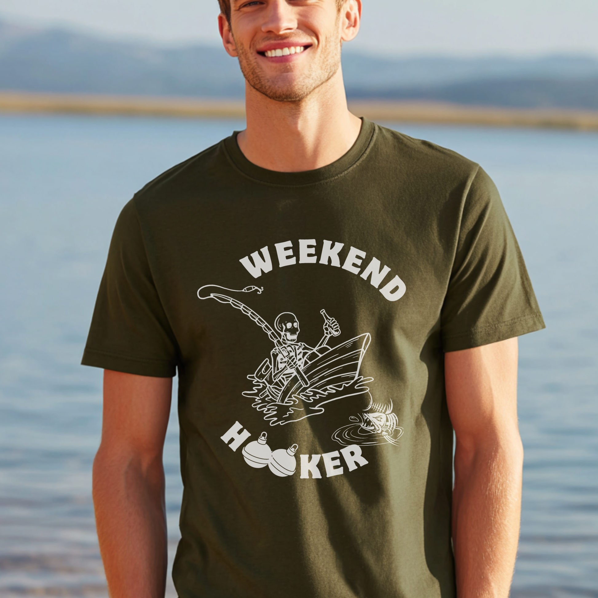 Man wearing a green t-shirt with a graphic design and text, standing by a body of water.