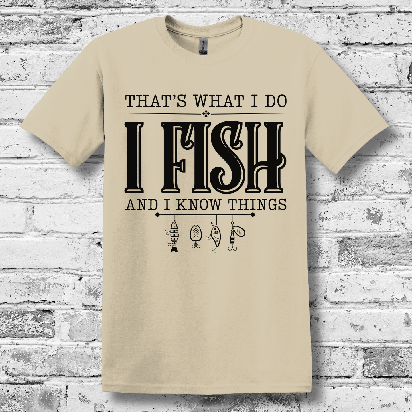 Beige t-shirt with text 'I Fish and I Know Things' on a brick wall background