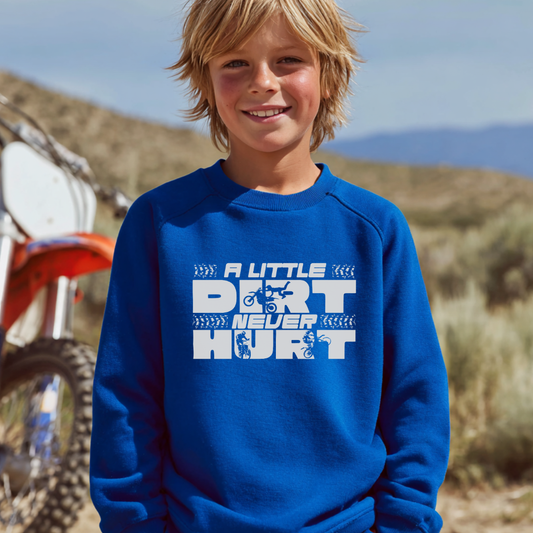 Child wearing a blue sweatshirt with text standing in front of a dirt bike in a desert setting