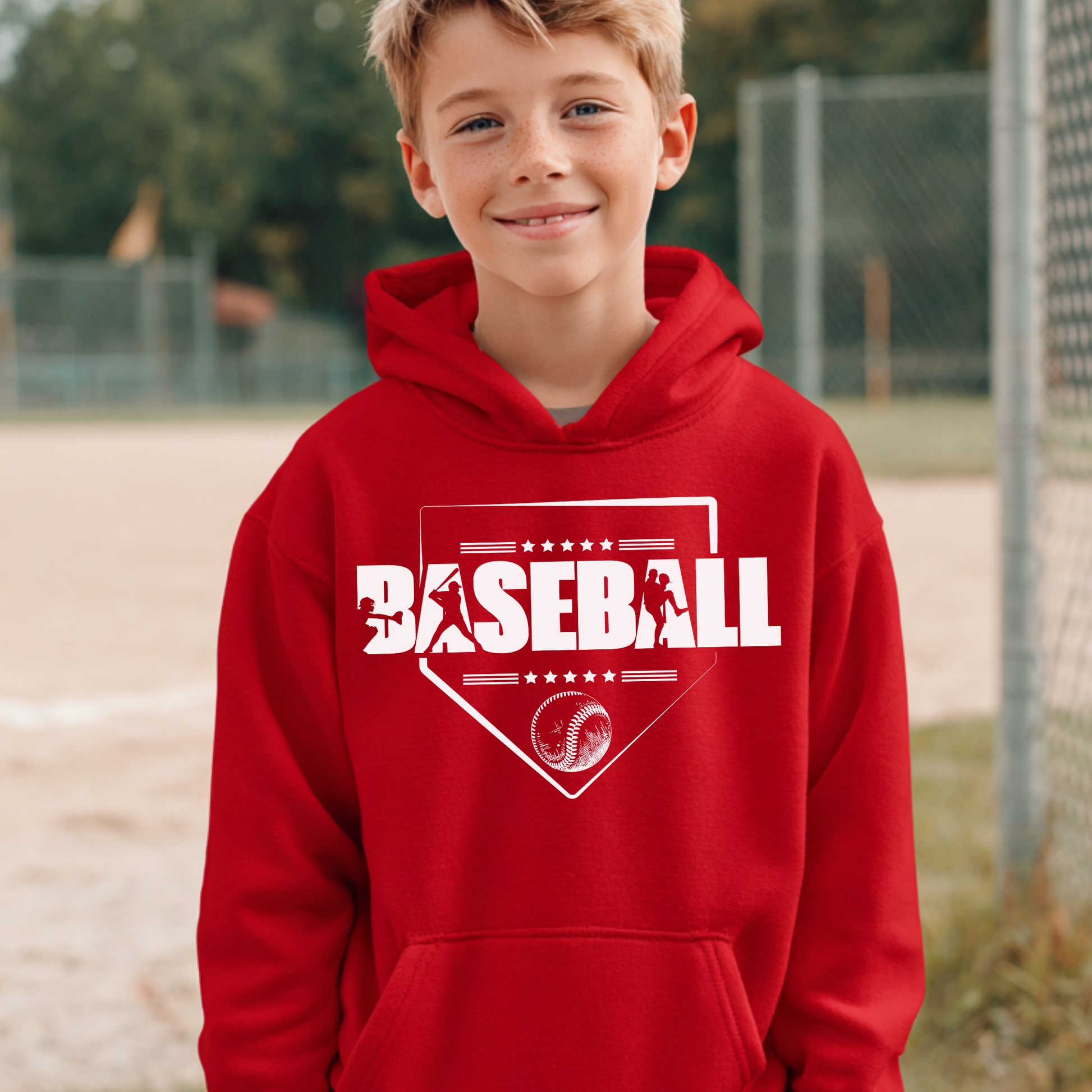 Child wearing a red hoodie with 'BASEBALL' printed on it, standing on a baseball field.