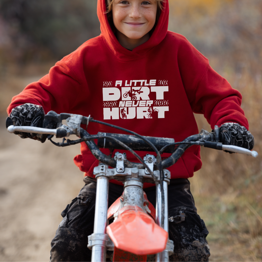 Child wearing a red hoodie with text on a dirt bike in an outdoor setting