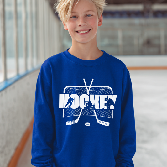 Child wearing a blue sweatshirt with a hockey design on an indoor ice rink.